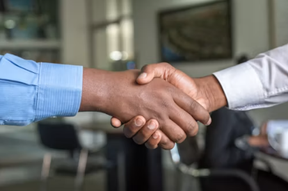 Two professionals shake hands in an office, confirming an agreement