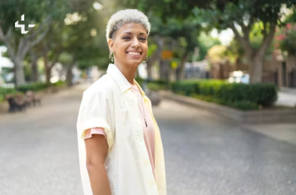 A woman with short silver hair smiles confidently while standing on a tree lined street